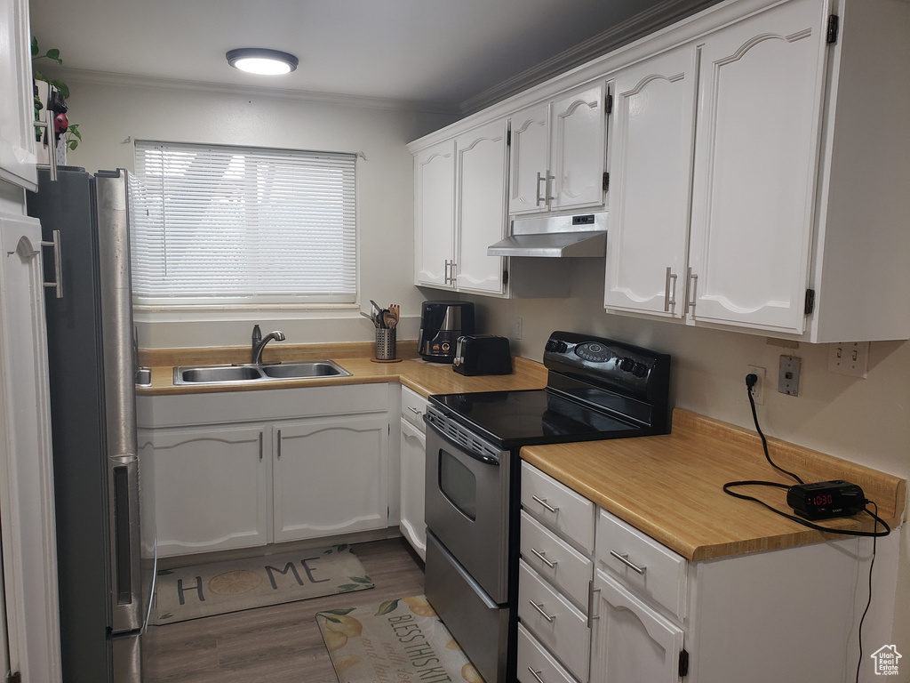 Kitchen with electric range oven, freestanding refrigerator, white cabinetry, a sink, and under cabinet range hood