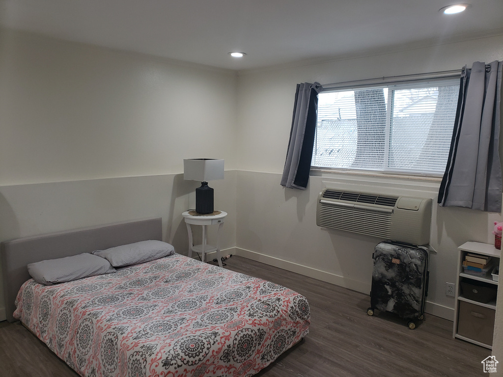 Bedroom featuring a wall mounted air conditioner, baseboards, wood finished floors, and recessed lighting