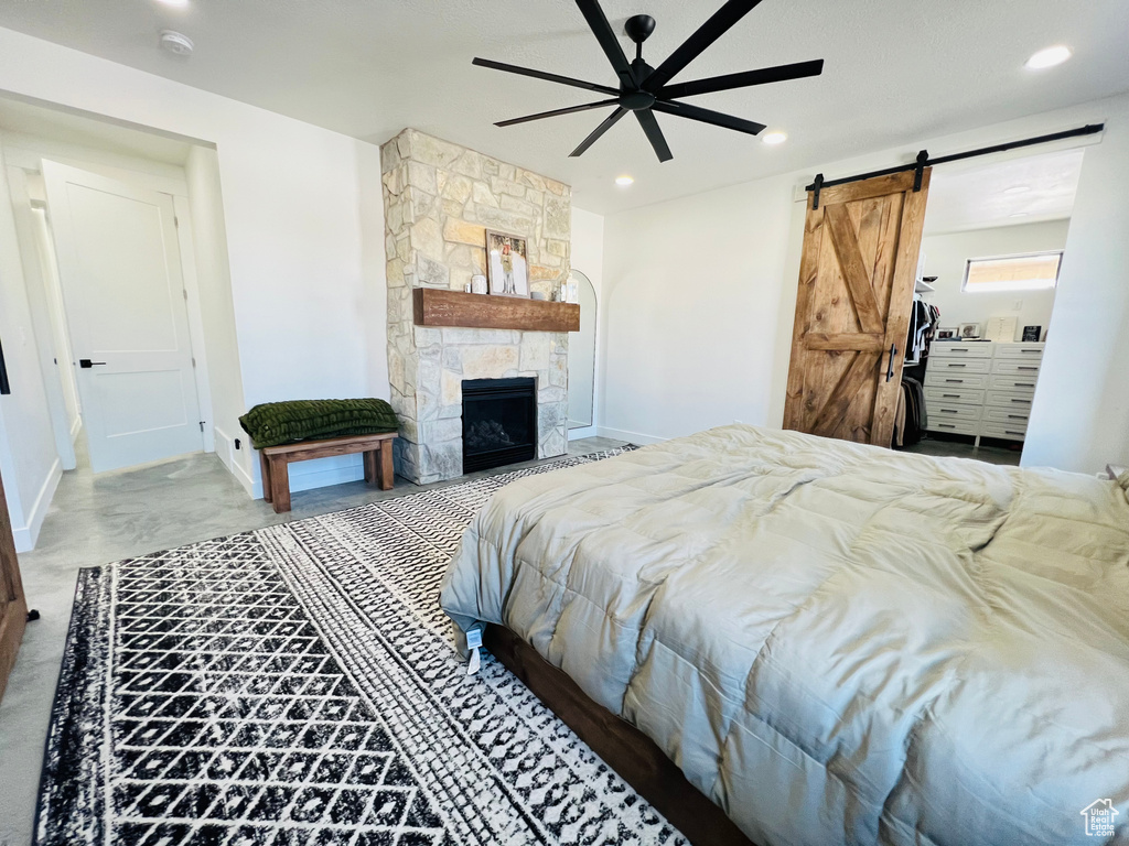 Bedroom with a barn door, baseboards, a ceiling fan, a stone fireplace, and recessed lighting