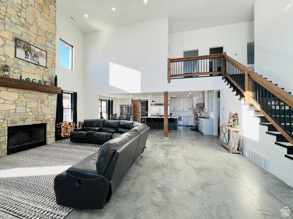 Living room featuring a fireplace, finished concrete flooring, visible vents, stairway, and plenty of natural light