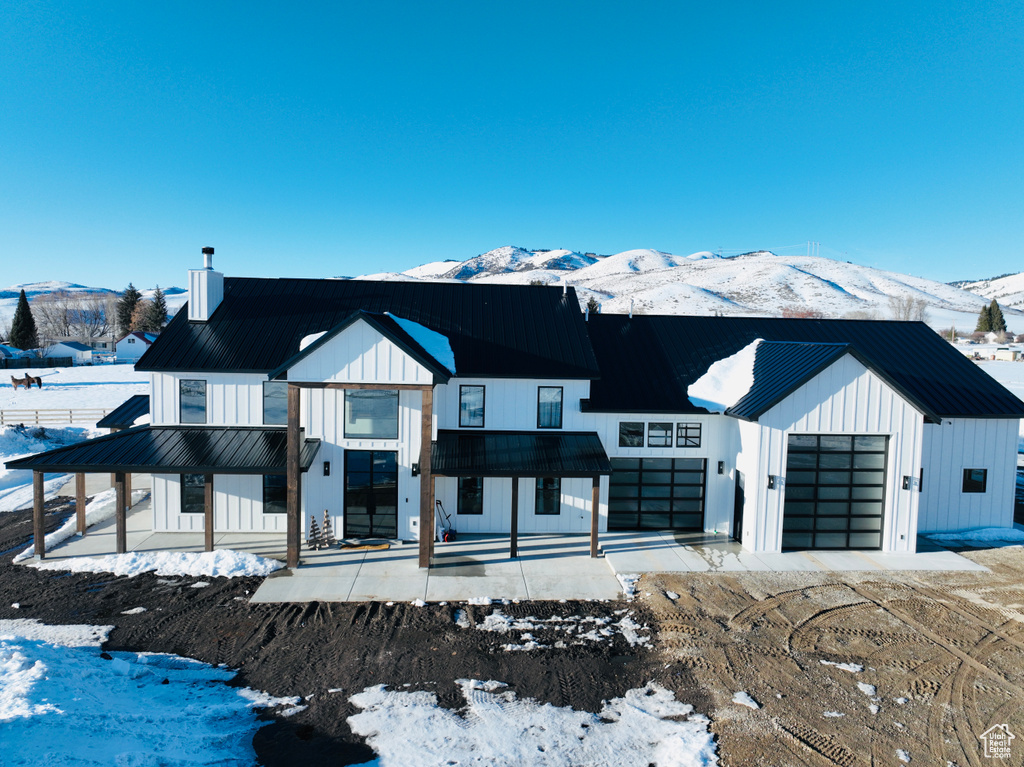 Modern inspired farmhouse with a chimney, board and batten siding, a standing seam roof, metal roof, and a mountain view