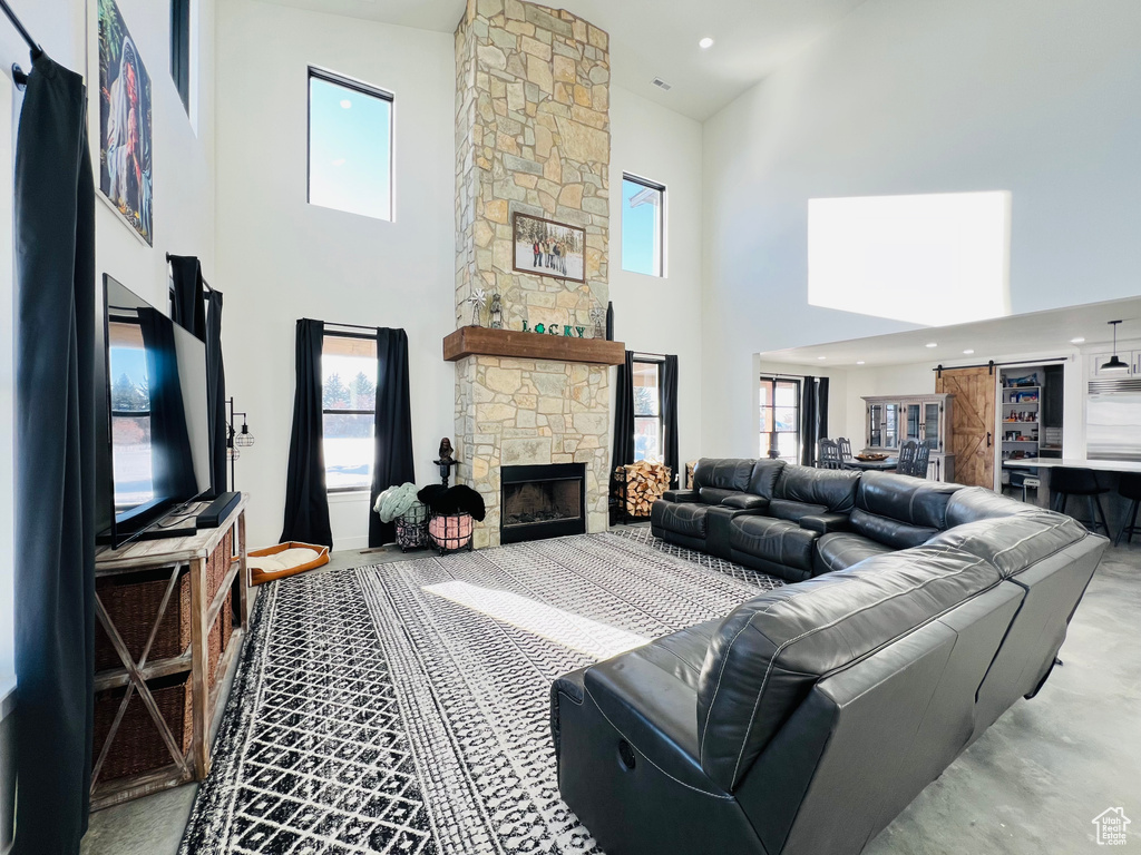 Living area with a towering ceiling, plenty of natural light, a fireplace, and recessed lighting