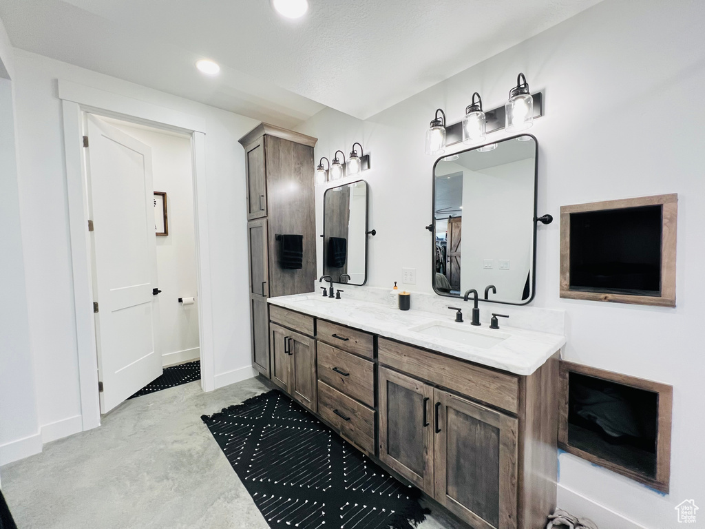 Bathroom with recessed lighting, a sink, baseboards, and double vanity