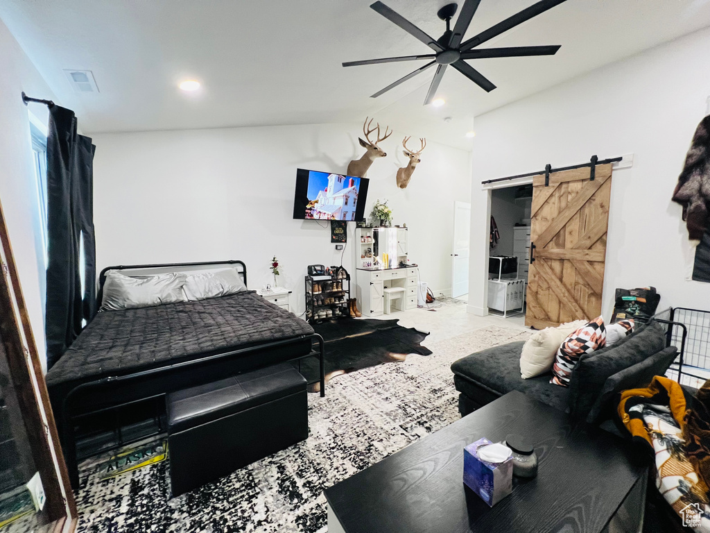 Bedroom with a ceiling fan, visible vents, vaulted ceiling, and a barn door
