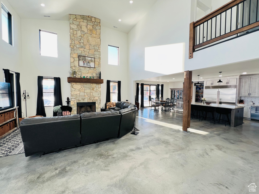 Living room with concrete floors, recessed lighting, a fireplace, and a towering ceiling