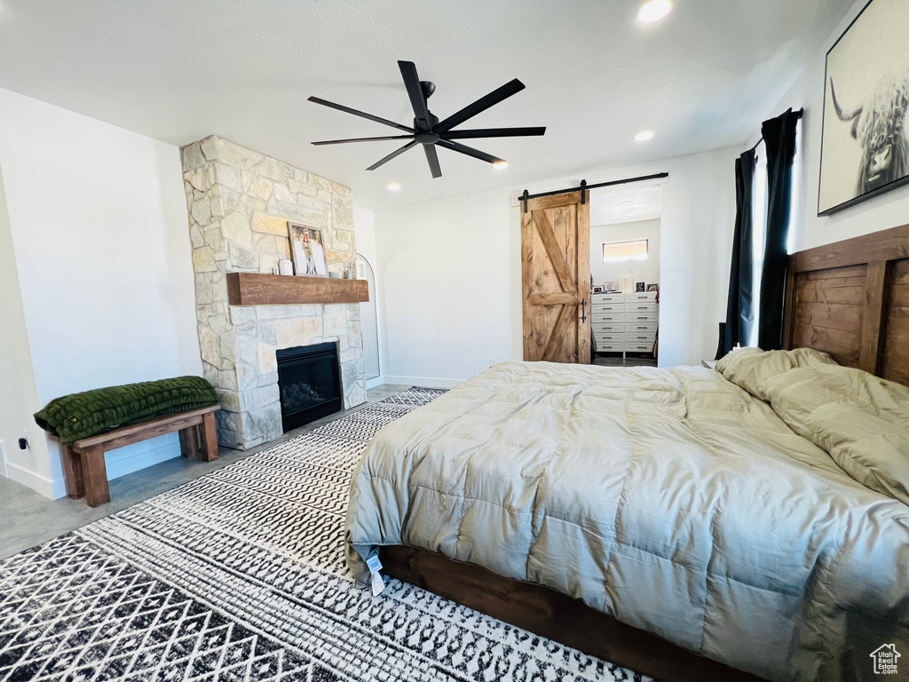 Bedroom featuring recessed lighting, a stone fireplace, baseboards, and a barn door