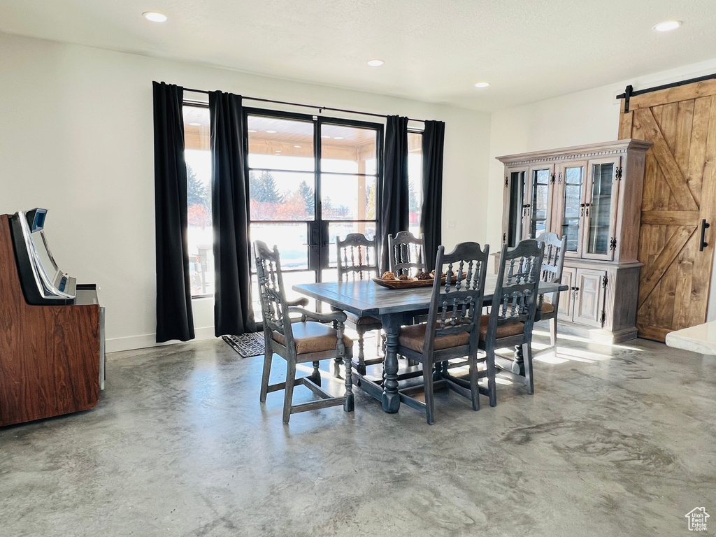 Dining space with concrete flooring, a barn door, baseboards, and recessed lighting