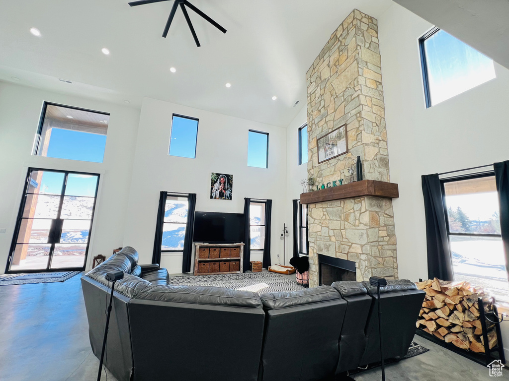 Living room featuring recessed lighting, finished concrete floors, a high ceiling, and a stone fireplace
