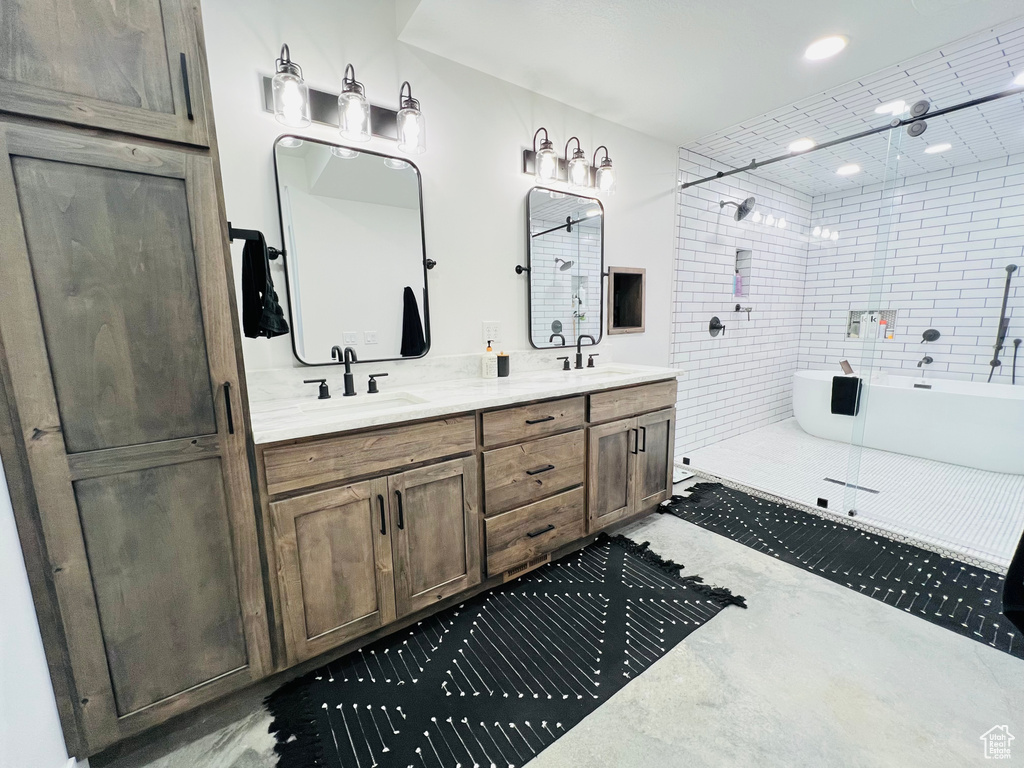 Full bath featuring double vanity, tiled shower, a freestanding tub, and a sink