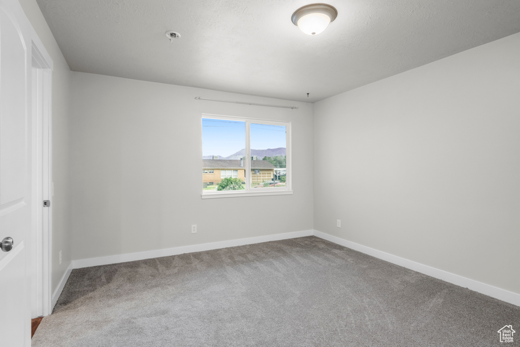 Carpeted spare room featuring baseboards