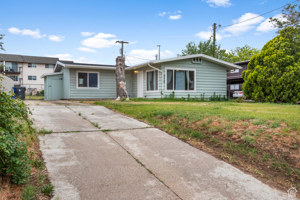 Ranch-style home with concrete driveway and a front yard