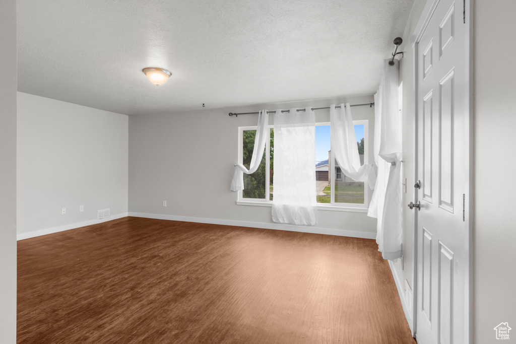 Spare room featuring wood finished floors, baseboards, and a textured ceiling