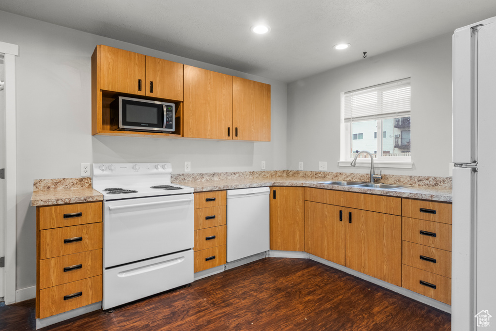 Kitchen with white appliances, a sink, dark wood finished floors, recessed lighting, and light countertops
