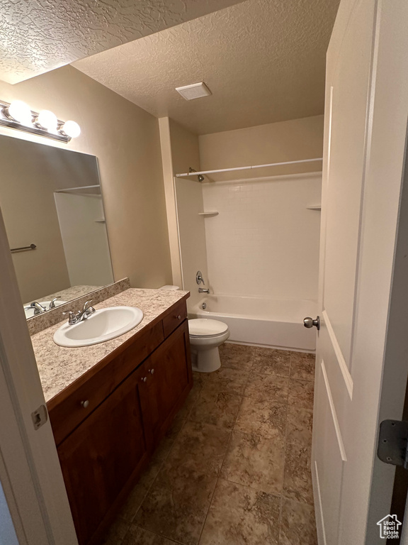 Full bath with toilet, washtub / shower combination, a textured ceiling, and vanity