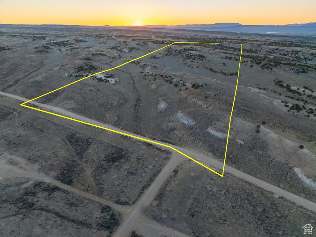 Aerial view at dusk featuring view of desert, a mountain view, and a rural view
