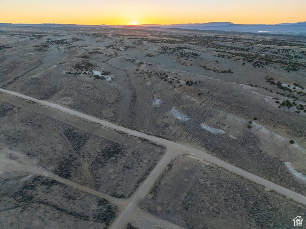 Aerial view at dusk featuring a mountain view, view of desert, and a rural view
