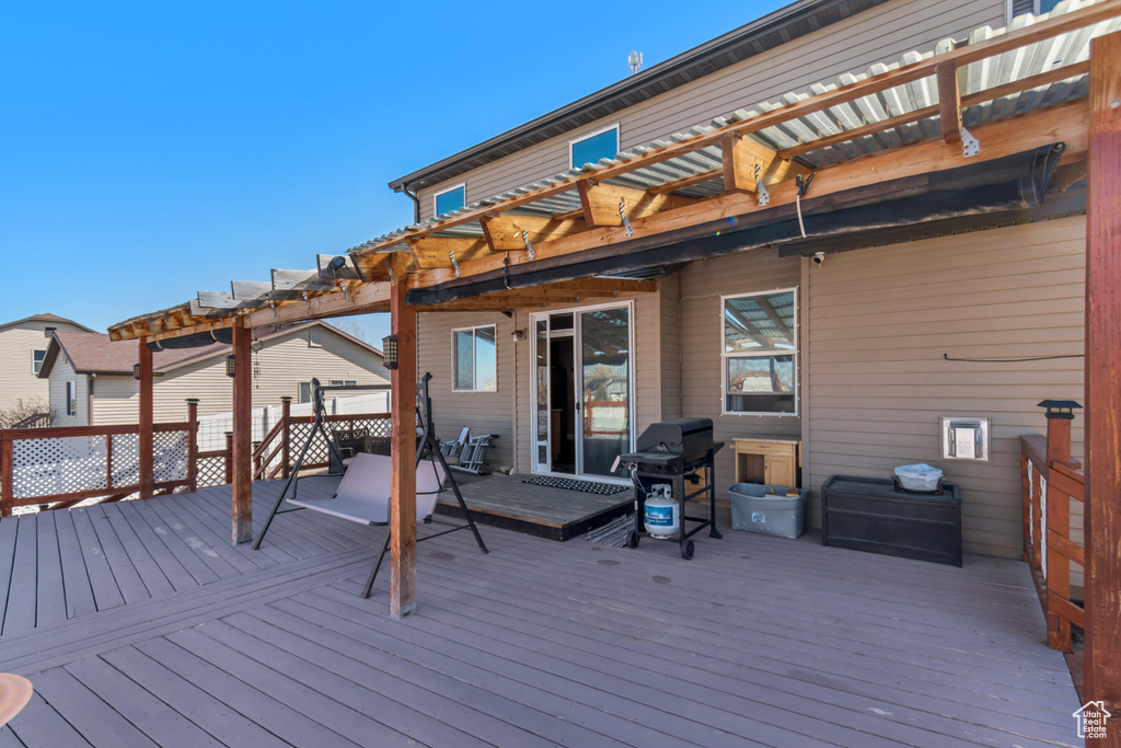 Wooden terrace featuring area for grilling and a pergola