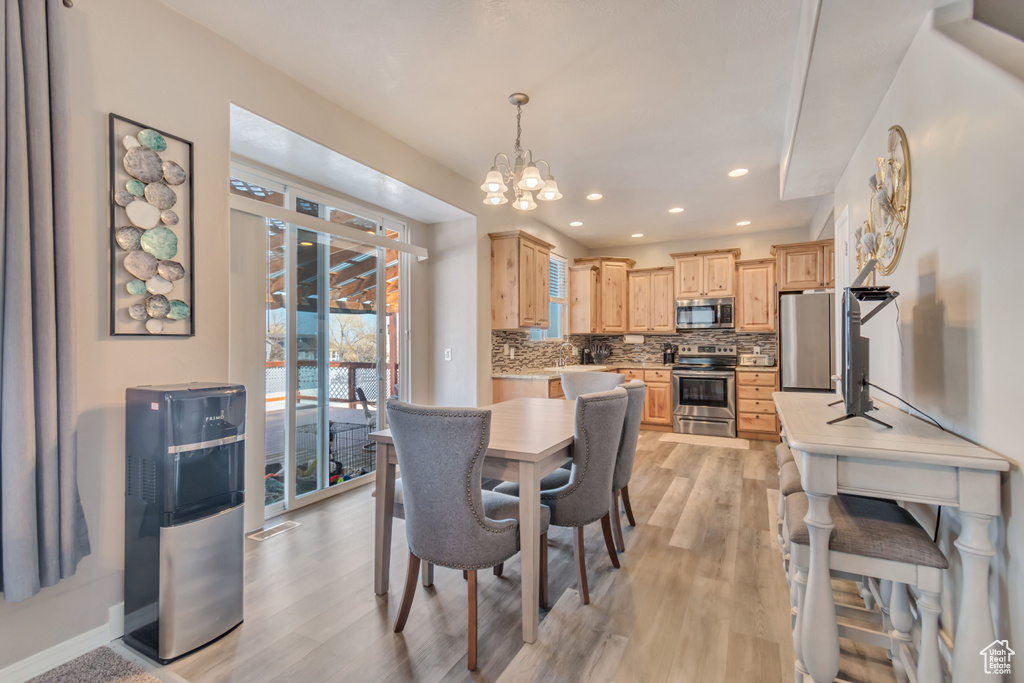 Dining room featuring light wood-style floors, baseboards, a chandelier, and recessed lighting