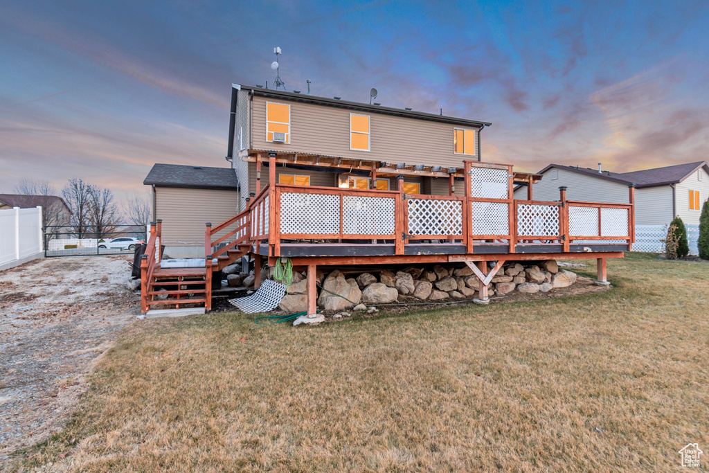 Rear view of house with fence, a deck, and a lawn