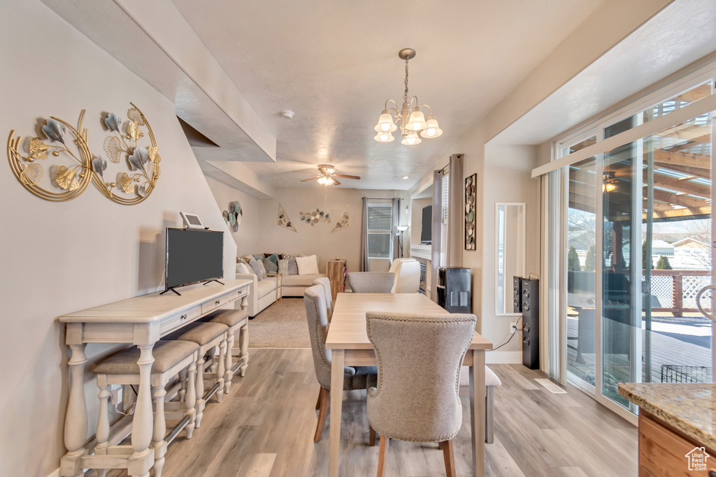 Dining space featuring ceiling fan with notable chandelier and light wood-type flooring