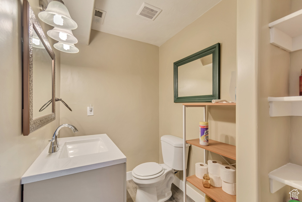 Bathroom featuring toilet, vanity, visible vents, and baseboards