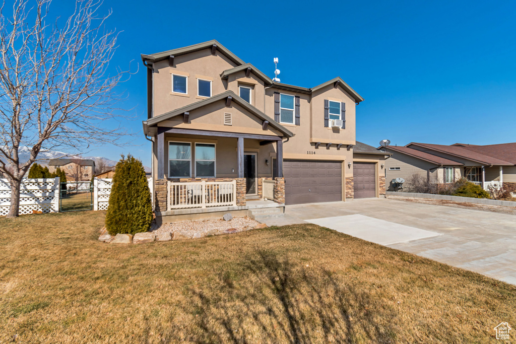 View of front of home with stucco siding, a porch, a garage, driveway, and a front lawn