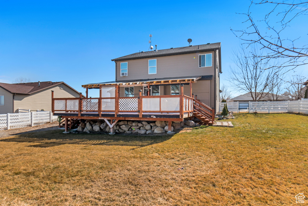 Back of house featuring a fenced backyard, a lawn, a wooden deck, and a pergola