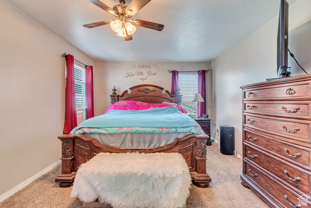 Bedroom with light carpet, a ceiling fan, and baseboards