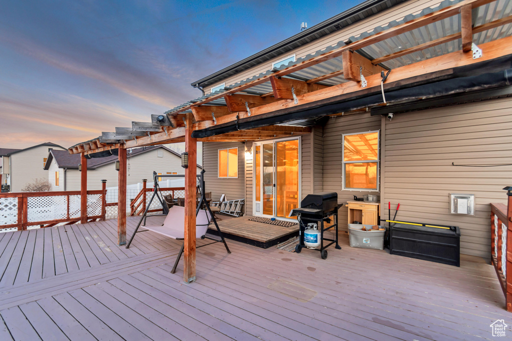 Deck at dusk featuring area for grilling and a pergola