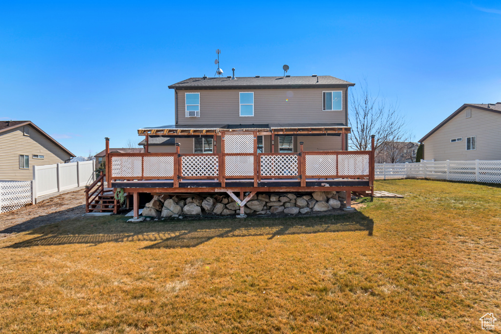 Back of property with a yard, a fenced backyard, a wooden deck, and a pergola