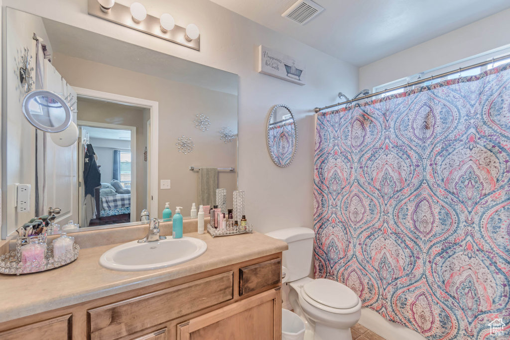 Full bathroom featuring toilet, curtained shower, visible vents, and vanity