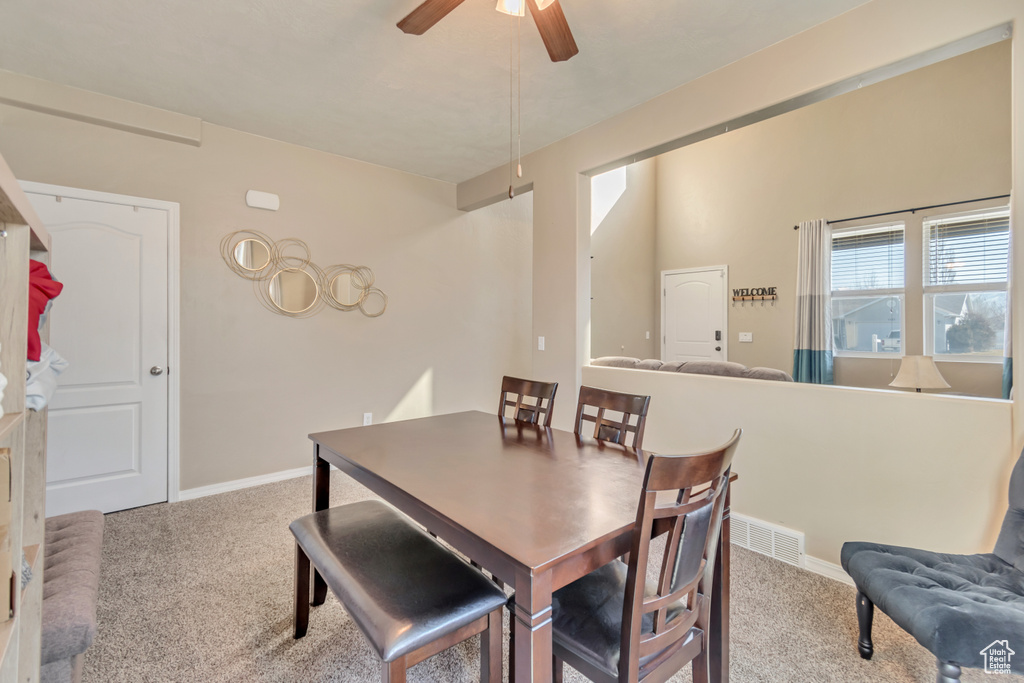 Carpeted dining space with visible vents, baseboards, and a ceiling fan