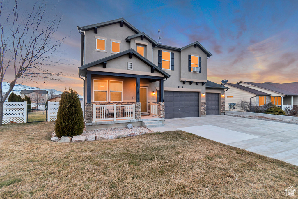 Traditional home featuring covered porch, stone siding, fence, and concrete driveway