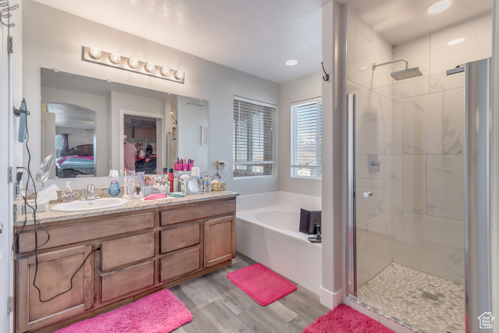 Bathroom featuring wood finished floors, a stall shower, a sink, and a bath