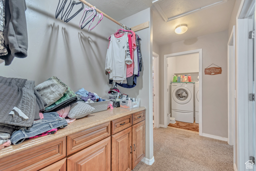 Spacious closet featuring attic access, washer and dryer, and light colored carpet