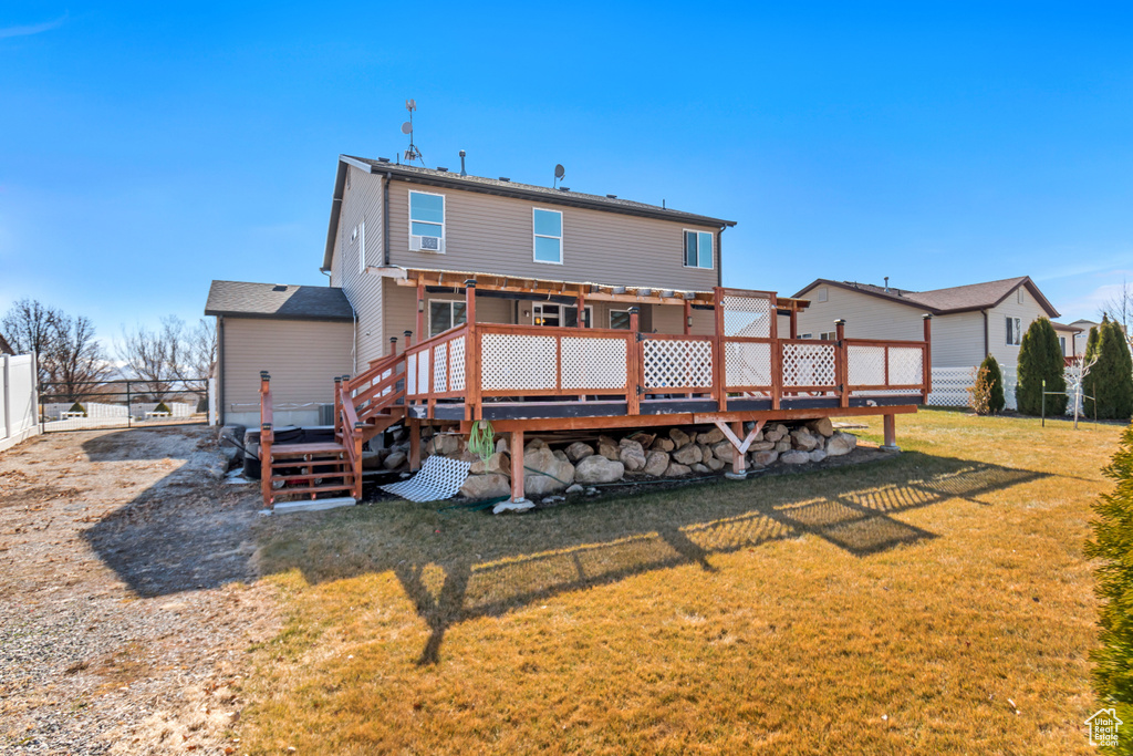 Rear view of property with a lawn, fence, and a wooden deck