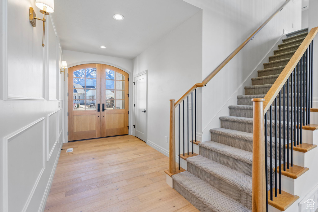 Foyer entrance featuring arched walkways, french doors, recessed lighting, light wood-type flooring, and stairs