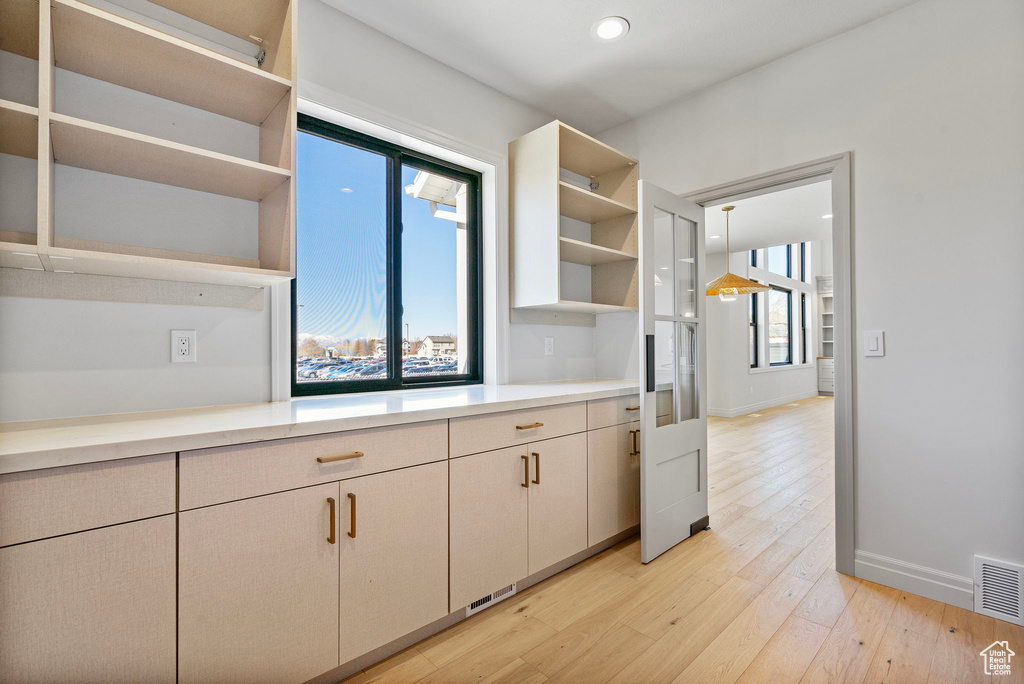 Kitchen featuring open shelves, light countertops, visible vents, light wood-type flooring, and baseboards