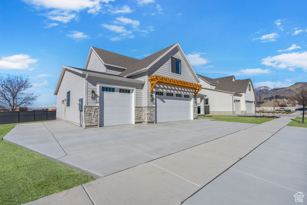 View of property exterior with a garage, a yard, stone siding, and concrete driveway