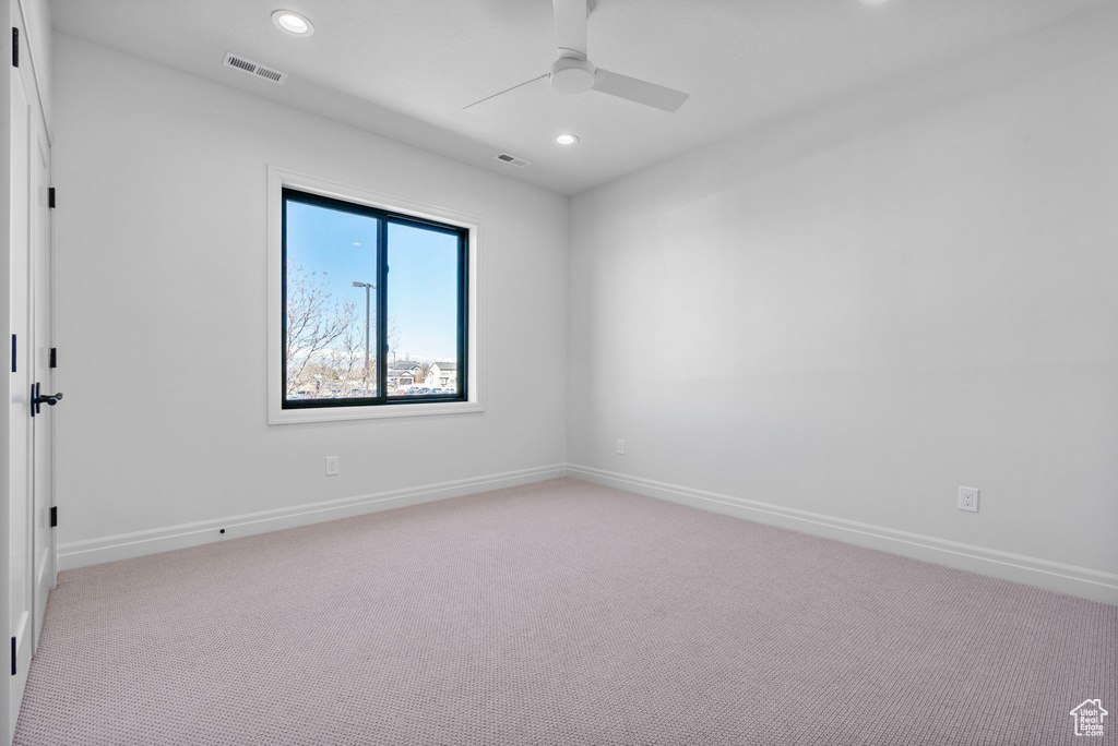 Empty room featuring light colored carpet, visible vents, baseboards, and recessed lighting