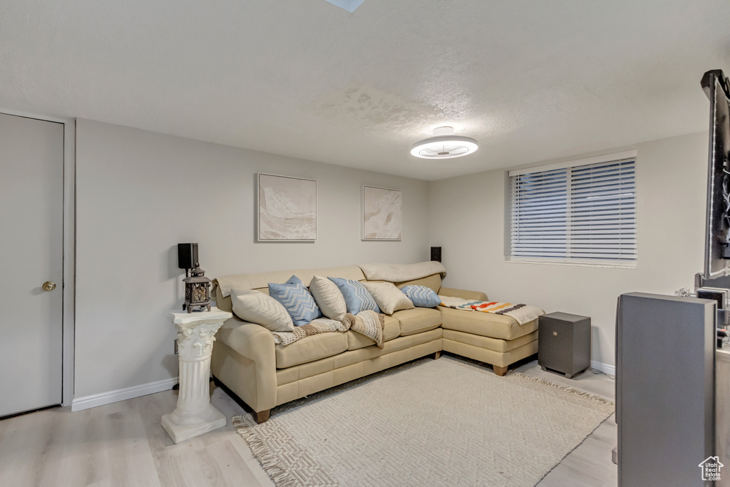 Living room featuring a textured ceiling, baseboards, and wood finished floors