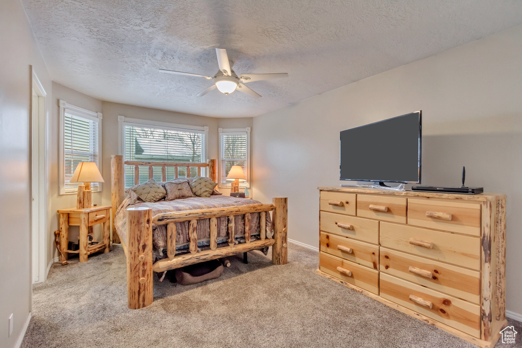 Bedroom featuring a textured ceiling, baseboards, a ceiling fan, and light colored carpet