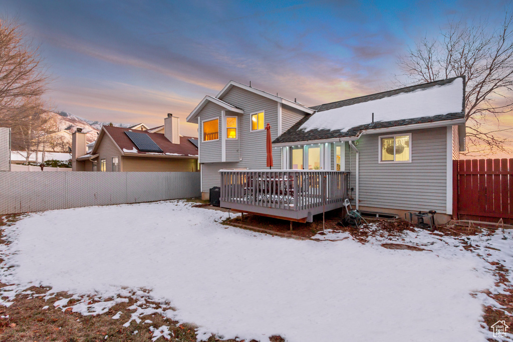 Snow covered property featuring a fenced backyard and a deck