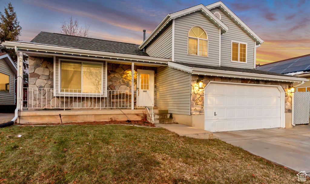 View of front of home with stone siding, covered porch, and concrete driveway