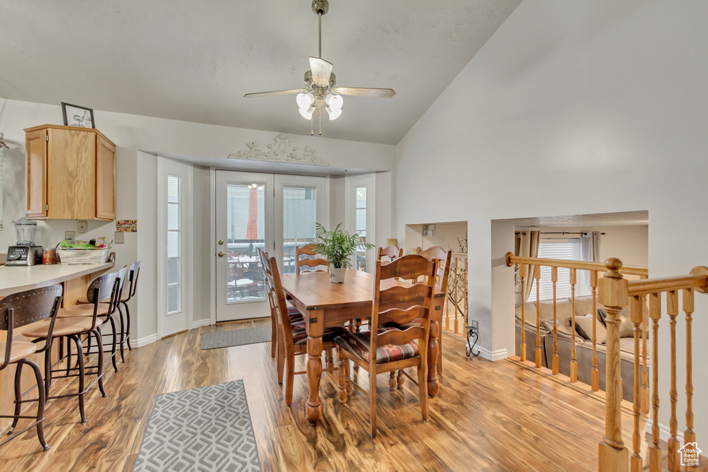 Dining room with light wood finished floors, a ceiling fan, baseboards, and high vaulted ceiling