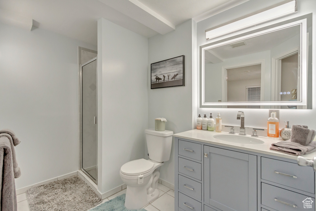 Bathroom featuring toilet, vanity, baseboards, a shower stall, and tile patterned floors