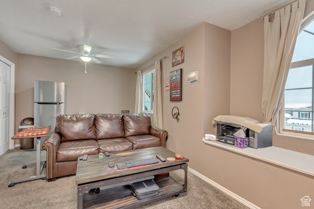 Carpeted living area with a wealth of natural light, ceiling fan, and baseboards