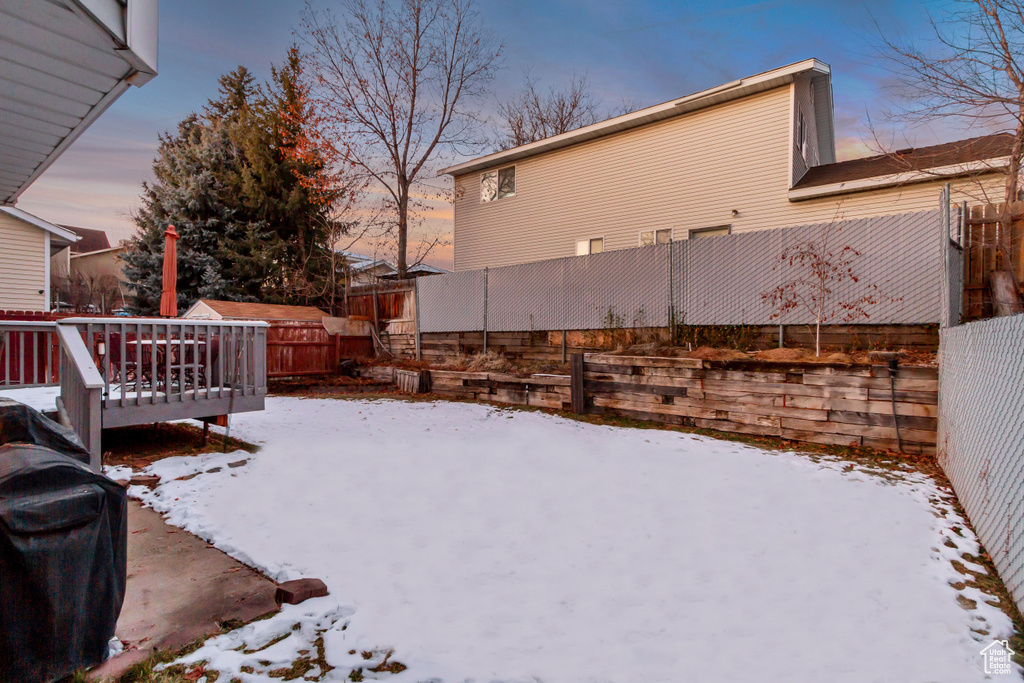 Yard covered in snow with fence and a wooden deck