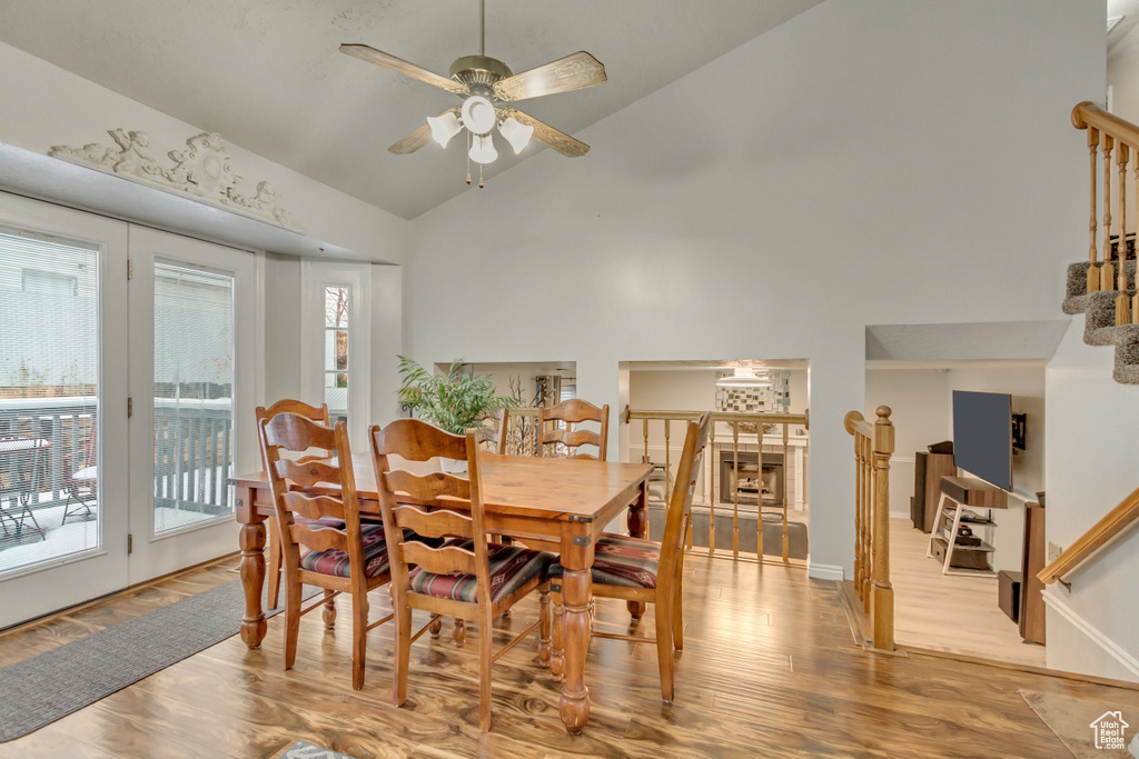 Dining space featuring ceiling fan, high vaulted ceiling, stairway, and wood finished floors