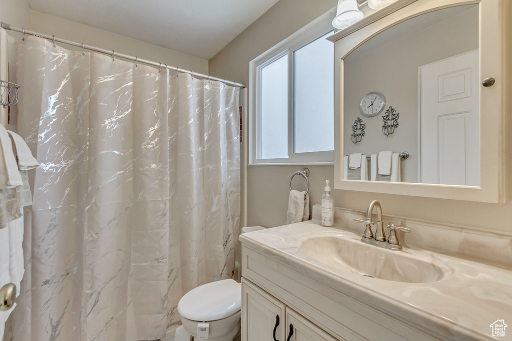 Bathroom with toilet, a shower with curtain, and vanity